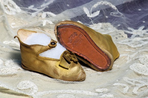PAIR OF GOLD SILK JUMEAU DOLL SHOES: PAIR OF GOLD SILK JUMEAU DOLL SHOES. Marks: 10 Bebe Jumeau Depose. 3 ¼” L. Gold silk-satin fabric with cotton lining, overcast edges, ankle-strap closing with buttons, gold silk bows accenting the 