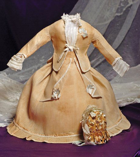 TWO-PIECE FRENCH FASHION GOWN WITH STRAW BONNET: TWO-PIECE FRENCH FASHION GOWN WITH STRAW BONNET. 5” shoulder width, 14” length. Fine buff-colored cotton made up in a jacket with ivory cotton edging and center front ties, shaped peplum back with