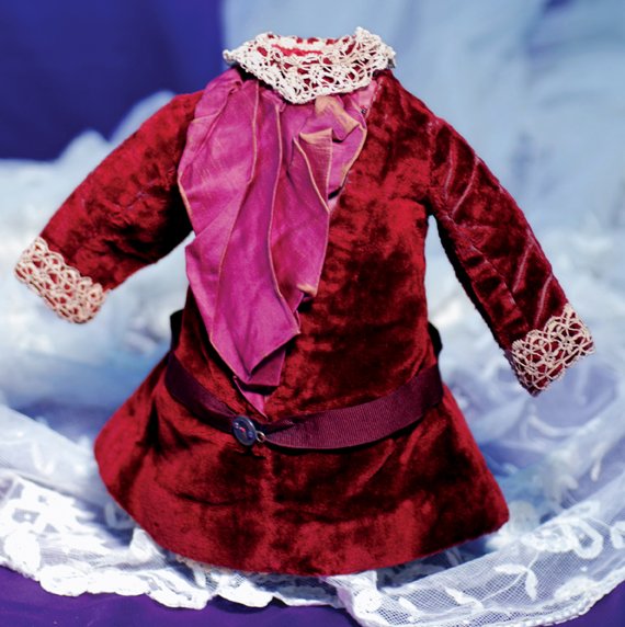 MAROON VELVET FRENCH BEBE DRESS: MAROON VELVET FRENCH BEBE DRESS. 5” shoulder width, 10” length. Dark maroon plush velvet frock with A-line front and silk-satin plastron, inset sleeves, scalloped-edged ecru lace trimmed sleeves, 