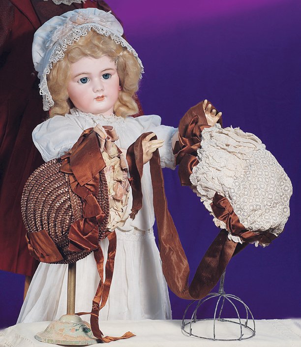 TWO ANTIQUE BONNETS FOR LARGE DOLLS: TWO ANTIQUE BONNETS FOR LARGE DOLLS. Each fits approximately 18” head circumference. 1) Woven brown straw bonnet with curved center back seam and 2 ½” brim decorated on the inside with large yell