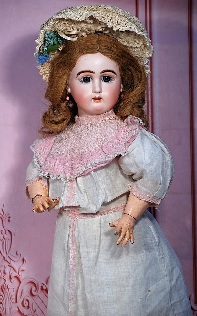 FRENCH BISQUE JULLIEN BEBE: 27” Marks: Jullien 10 Bisque socket head, inset blue glass paperweight eyes, painted lashes, eyeliner, mauve-blushed eye shadow, feathered and brushstroked brows, pierced ears, open mouth, shade