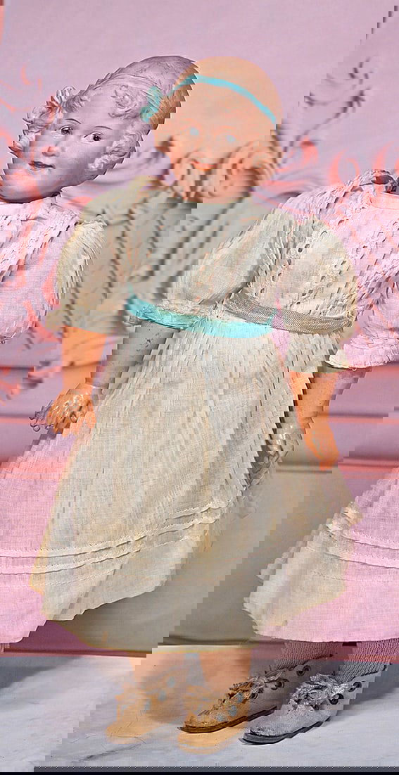 GERMAN BISQUE ’COQUETTE’ CHARACTER GIRL BY GEBRUDER HEUBACH: 12” Marks: 7786 Heubach (in square) Bisque socket head, sculpted dark blonde hair with aqua hair band and bow, painted features, side-glancing intaglio blue eyes, upper eyeliner, tapered brows, open