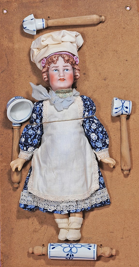 GERMAN BISQUE PRESENTATION CARD WITH REVALO CHARACTER AS CHEF: 15” x 8” Heavy card stock presentation card features display of blue and white porcelain chef tools and a bisque head character girl by Gebruder Olhaver having bisque socket head with deep