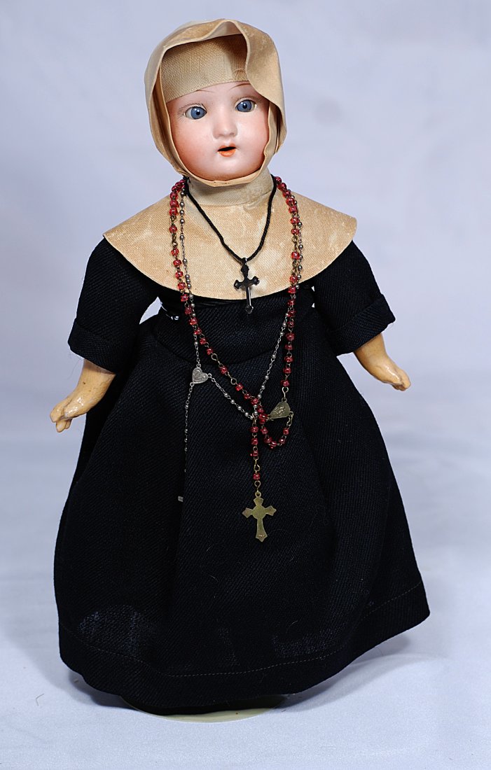 PETITE GERMAN BISQUE NUN DOLL IN ORIGINAL COSTUME: 11” Bisque socket head, blue sleep eyes, painted lashes, tapered brows, open mouth, upper teeth, composition jointed body, original nun habit Commentary: All-original doll; costume has not been