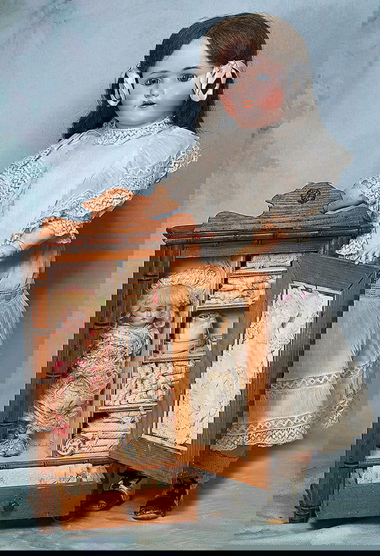 GERMAN BISQUE DOLL IN PRESENTATION CABINET WITH TOILETTE AND ACCESSORY ITEMS: GERMAN BISQUE DOLL IN PRESENTATION CABINET WITH TOILETTE AND ACCESSORY ITEMS. Doll 8 ½”; Cabinet 17”. A maple wood cabinet with faux bamboo details holds a German bisque doll with s