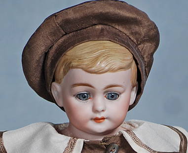 GERMAN BISQUE DOLL KNOWN AS “AMERICAN SCHOOL BOY”.: 13. GERMAN BISQUE DOLL KNOWN AS “AMERICAN SCHOOL BOY”. 14”. Bisque shoulderhead with sculpted blonde hair, inset blue glass eyes, painted lashes, feathered brows, closed mouth, kid