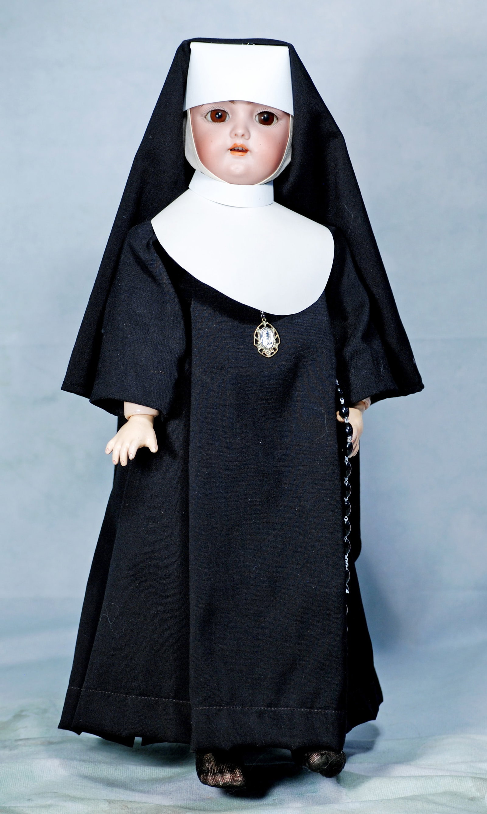 GERMAN BISQUE DOLL IN NUN COSTUME, BY HANDWERCK: 18. GERMAN BISQUE DOLL IN NUN COSTUME, BY HANDWERCK. 17”. Marks: 109. Bisque socket head, brown sleep eyes, painted lashes, feathered brows, open mouth, accented lips, upper teeth, pierced ears,