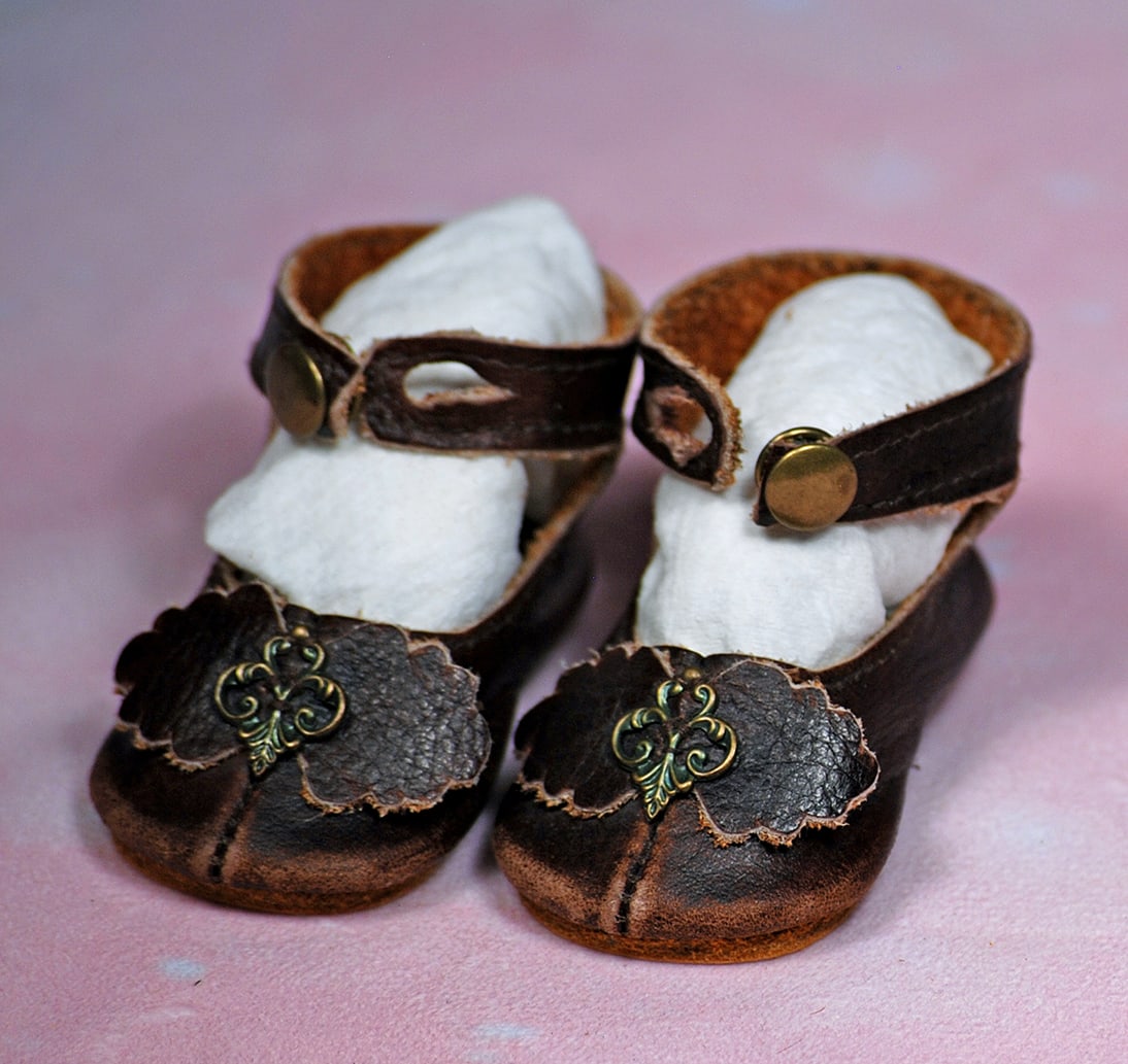 PAIR OF ANTIQUE LEATHER DOLL SHOES. 2 ½”. Rich brown leather shoes with ankle-strap: PAIR OF ANTIQUE LEATHER DOLL SHOES. 2 ½”. Rich brown leather shoes with ankle-strap button closing, scalloped-edge leather bows, leather soles. Commentary: Original factory shoes, very good