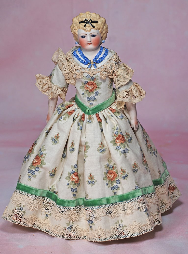 GERMAN BISQUE LADY WITH SCULPTED HAIR AND BODICE. 12 ½”. Bisque shoulderhead, sculpted: GERMAN BISQUE LADY WITH SCULPTED HAIR AND BODICE. 12 ½”. Bisque shoulderhead, sculpted blonde hair in curly fashion accented with black ribbon and bow, pierced ears, inset blue glass eyes, 