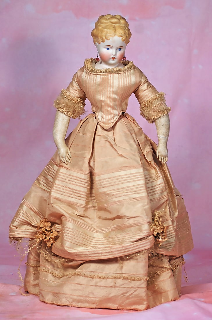 GERMAN BISQUE LADY WITH SCULPTED COIFFURE AND ANTIQUE GOWN.: GERMAN BISQUE LADY WITH SCULPTED COIFFURE AND ANTIQUE GOWN. 17”. Marks: None. Bisque shoulderhead turned slightly to the left, sculpted blonde hair in elaborate coiffure having braided coronet a