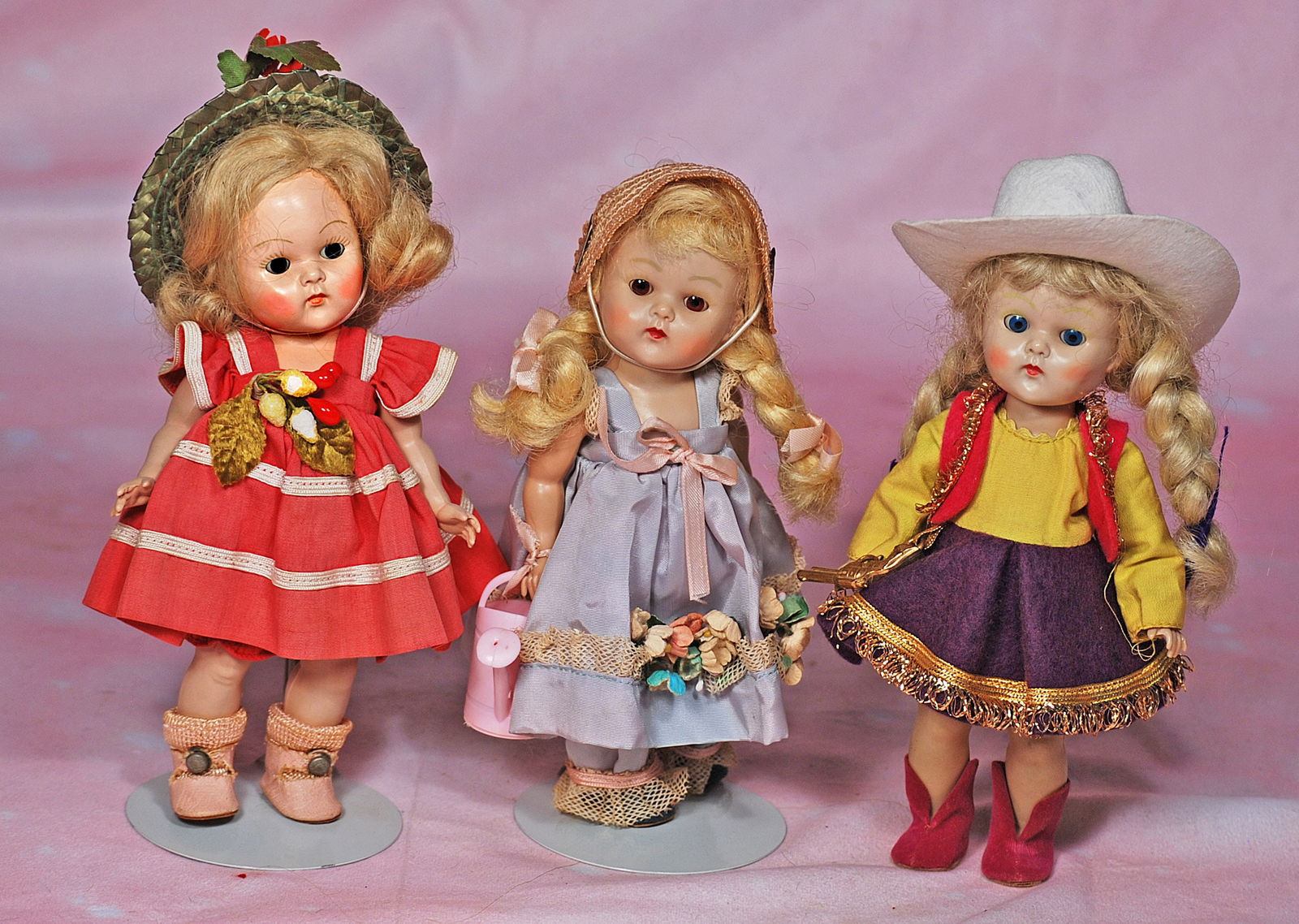 THREE PAINTED-LASH VOGUE GINNY DOLLS.: 76. THREE PAINTED-LASH VOGUE GINNY DOLLS. 8”. Hard plastic dolls, painted lashes, sleep eyes, original blonde wig; 1953 Tiny Miss “Glad” in original red costume, green straw hat, pink ce