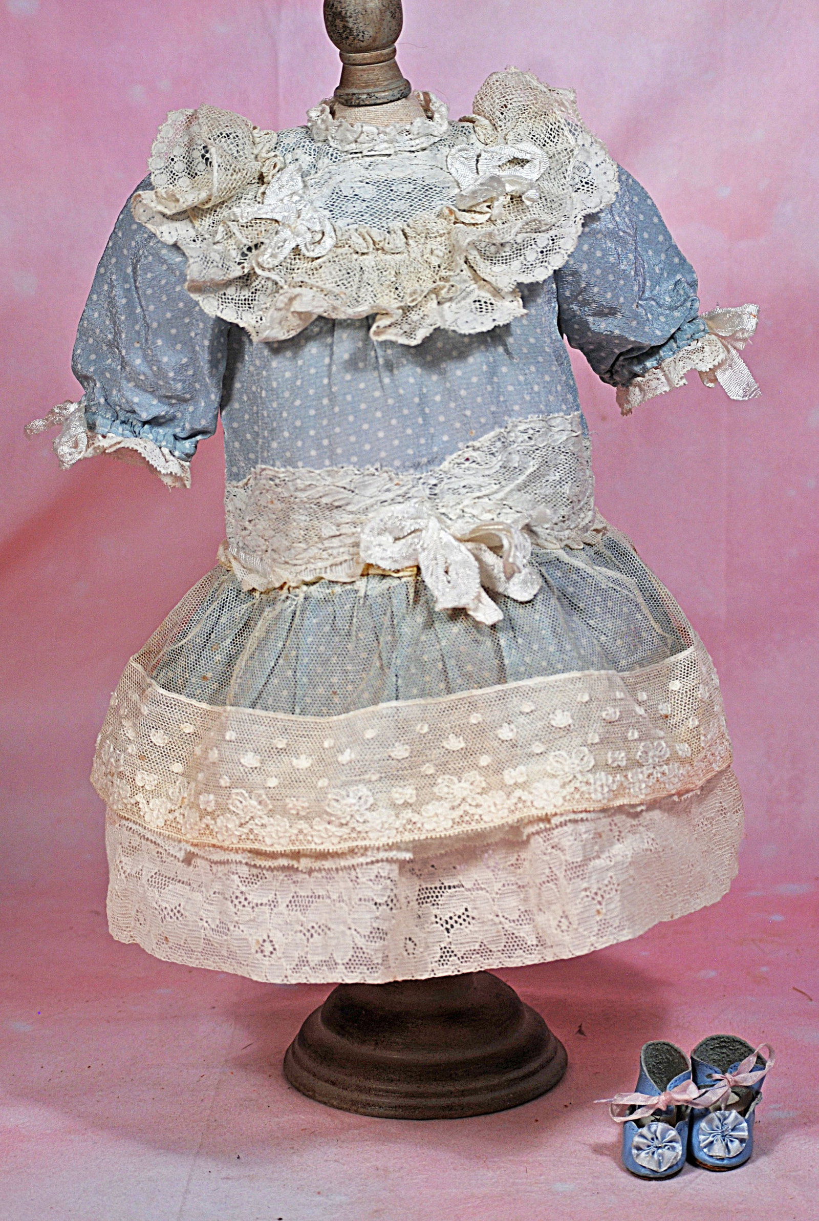 DOLL DRESS AND SHOES: 133. DOLL DRESS AND SHOES. Blue and white dot silk crepe dress has inset lace yoke, puffed sleeves, dropped waist, gathered skirt with net and lace overskirt, back button closing, 5” shoulder wi