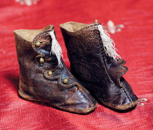 PAIR OF BROWN LEATHER FASHION BOOTS. 2 ¾” length.: PAIR OF BROWN LEATHER FASHION BOOTS. 2 ¾” length. Dark brown soft leather boots with leather soles, four-button side closing, stitching detail at edges, ivory tassels. Commentary: Two buttons missi