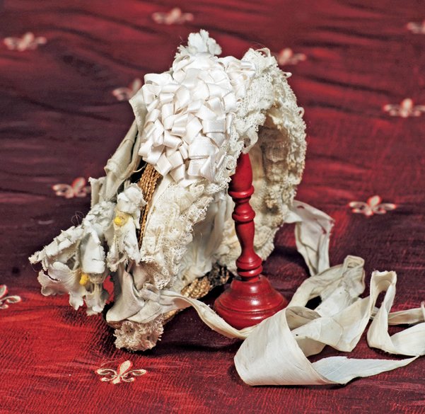 ANTIQUE STRAW BONNET WITH LAVISH ADORNMENT. 3 ¾” i: ANTIQUE STRAW BONNET WITH LAVISH ADORNMENT. 3 ¾” inside cap width. Natural woven straw bonnet has brim of triple-layered and tightly-pleated lace accented with cluster of silk rosettes; back adorne