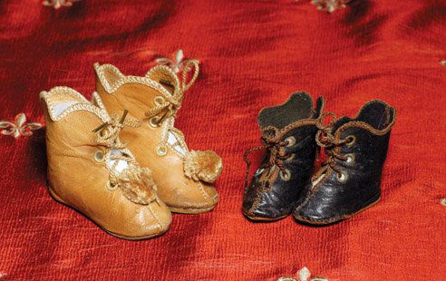TWO PAIR OF ANTIQUE FRENCH LEATHER DOLL BOOTS. 2: TWO PAIR OF ANTIQUE FRENCH LEATHER DOLL BOOTS. 2 ¾” pair of camel tan leather boots with overcast edges, metal tipped cord ties, tan pom poms, leather soles incised “8”; 1 ¾” L. pair of blac