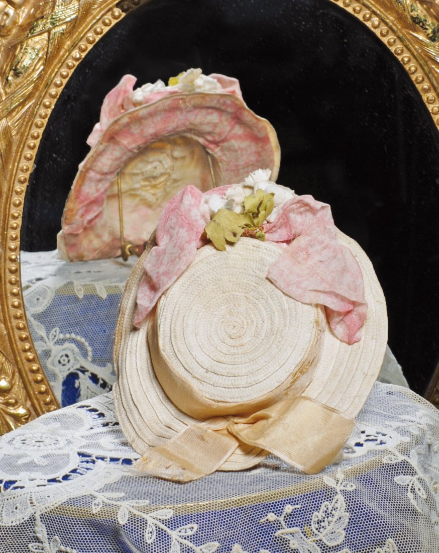FINE ANTQUE WHITE STRAW DOLL BONNET. 2 ½” inside: FINE ANTQUE WHITE STRAW DOLL BONNET. 2 ½” inside cap width. Woven white straw bonnet has flattened crown, 1 ¼” brim, rose-pink organdy bows and inside brim, pink silk band, flowers at center. Co