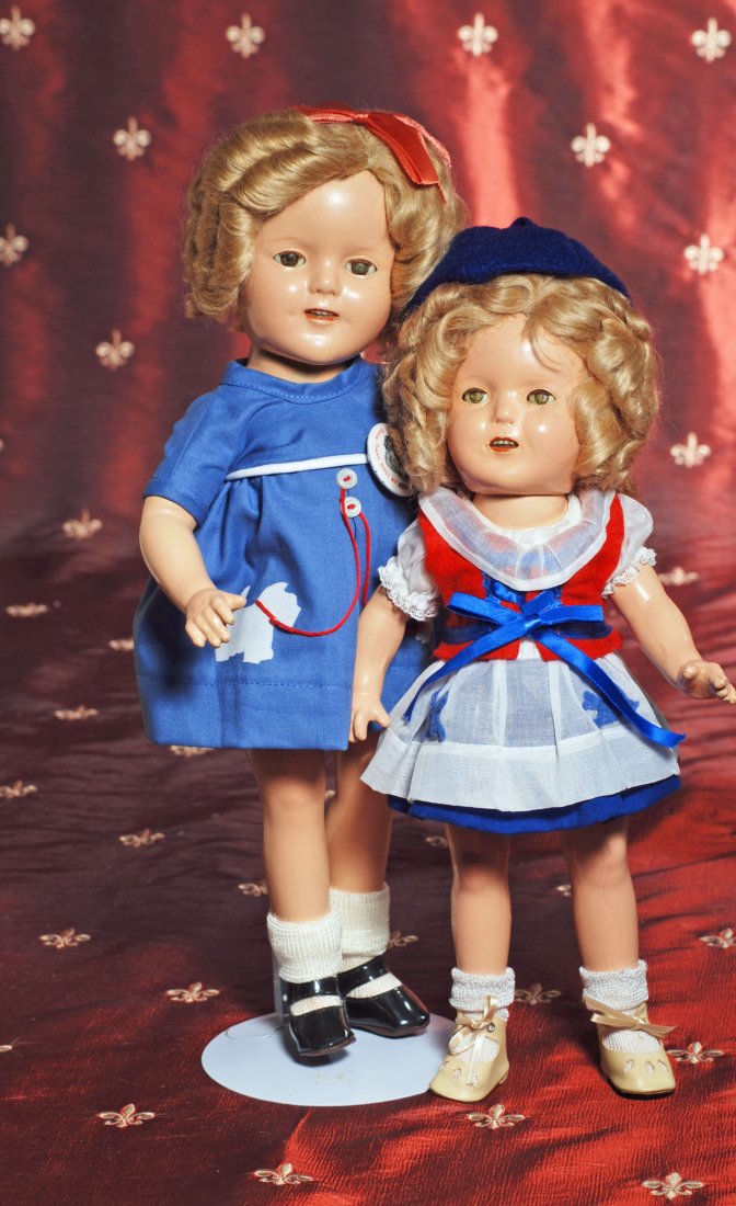 TWO REDRESSED SHIRLEY TEMPLE DOLLS.: TWO REDRESSED SHIRLEY TEMPLE DOLLS. 13” and 16”. Each is composition socket head on five-piece body, original mohair wig, sleep eyes, dressed in copy of blue cotton Scottie dress and copy of the B