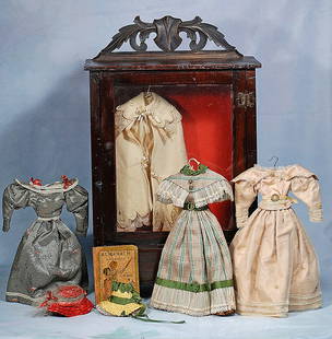 ANTIQUE WARDROBE CABINET WITH COSTUMES FOR MILLINER MODEL DOLL: ANTIQUE WARDROBE CABINET WITH COSTUMES FOR MILLINER MODEL DOLL. 19” x 11 ½” x 9 ½”. Wooden wardrobe closet with glass door and one lower drawer; contains two silk dresses w