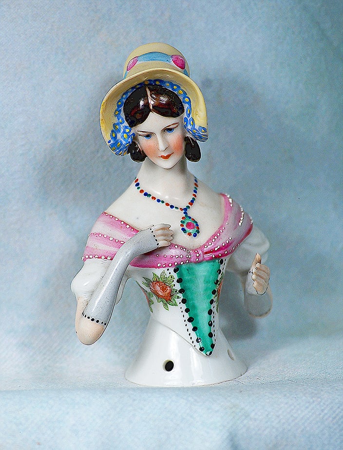 GERMAN PORCELAIN HALF DOLL LADY IN YELLOW BONNET: GERMAN PORCELAIN HALF DOLL LADY IN YELLOW BONNET. 4”. Waist-up porcelain lady with brown sculpted ringlet curls under yellow sunbonnet with floral trim on the inner brim and blue band and bow at