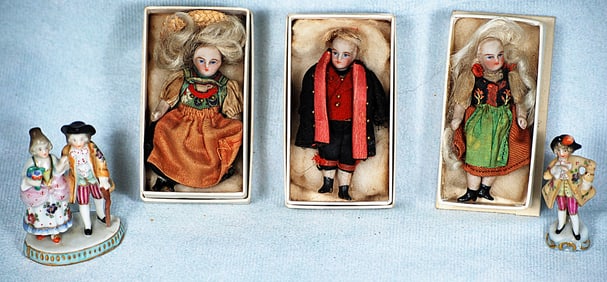 THREE MINIATURE BISQUE DOLLS AND TWO MINIATURE PORCELAIN FIGURINES.
