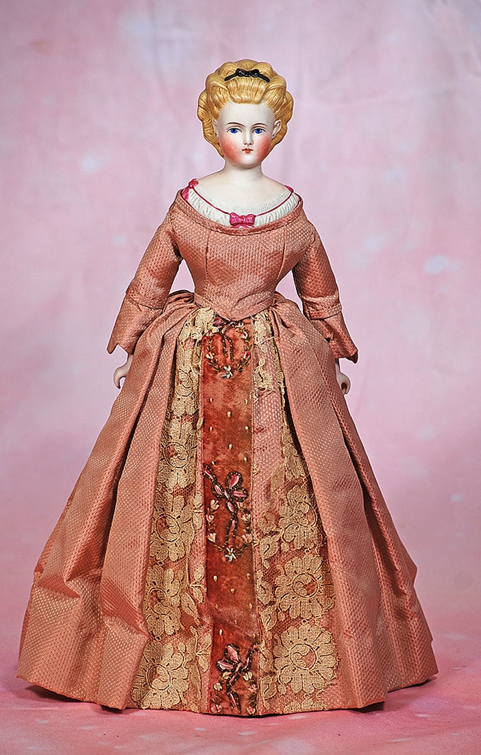 GERMAN BISQUE LADY WITH SCULPTED HAIR AND BODICE: GERMAN BISQUE LADY WITH SCULPTED HAIR AND BODICE. 13”. Marks: None. Bisque shoulderhead, sculpted blonde hair waved high in the front and accented with black ribbon and bow, pierced ears, painte