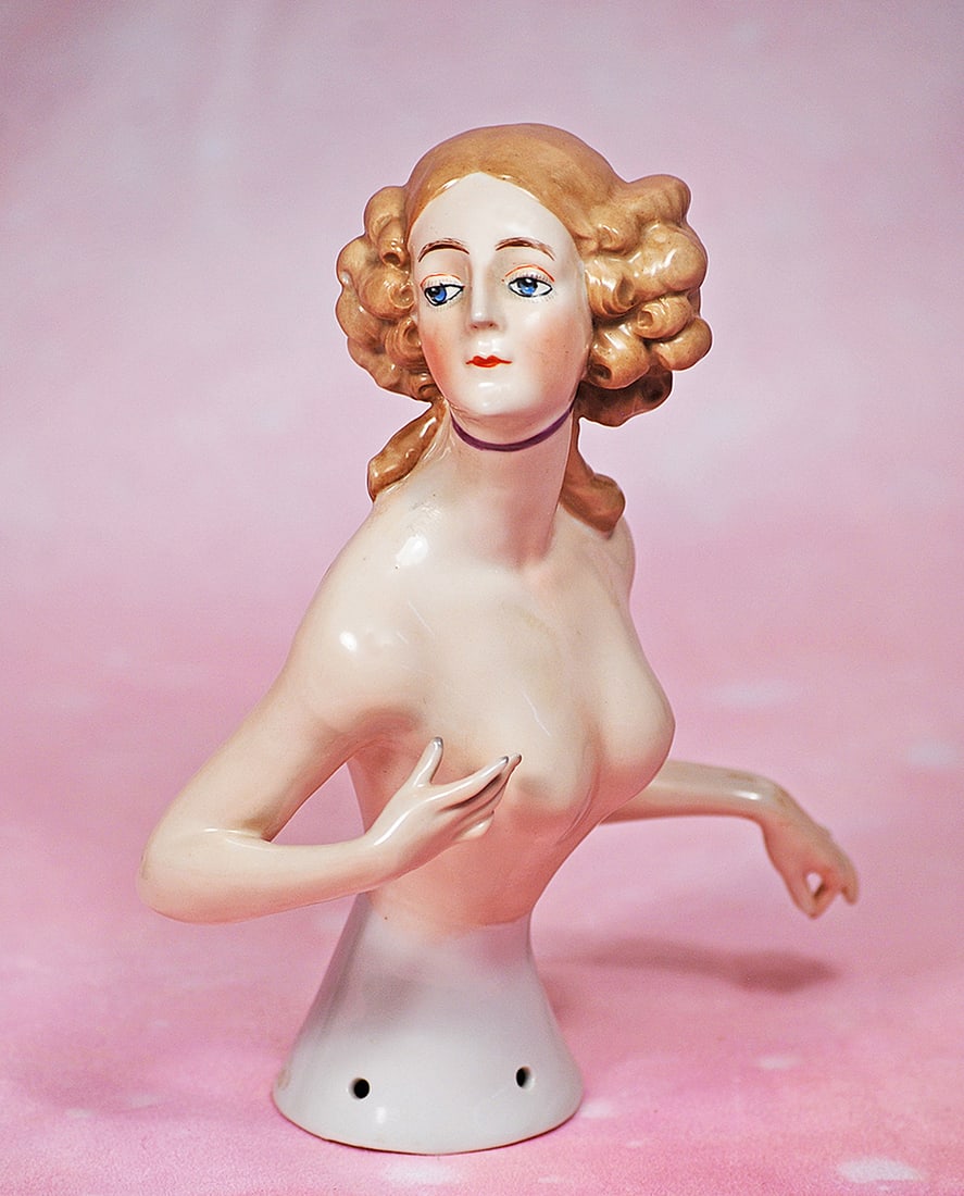 LARGE GERMAN PORCELAIN HALF DOLL BY GOEBEL: LARGE GERMAN PORCELAIN HALF DOLL BY GOEBEL. 7 ½”. Marks: Goebel trademark symbol. Waist-up nude porcelain figure of adult lady with voluptuous bosom, oval head turned sharply to the right,