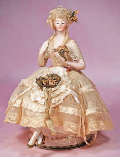 GERMAN BISQUE HALF DOLL AS POWDER BOX: GERMAN BISQUE HALF DOLL AS POWDER BOX. 9” overall. Waist-up bisque doll with painted features, blue downcast eyes, tapered brows, closed mouth, blonde mohair wig, arms posed away from body