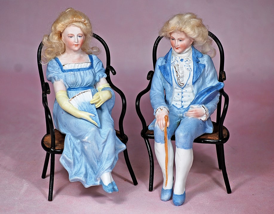 GERMAN BISQUE COUPLE IN SEATED POSE WITH BENTWOOD CHAIRS: GERMAN BISQUE COUPLE IN SEATED POSE WITH BENTWOOD CHAIRS. 7 ½”. Marks: None. Each is all-bisque with painted features, blue eyes, closed mouth, blonde mohair wig, sculpted blue and white co