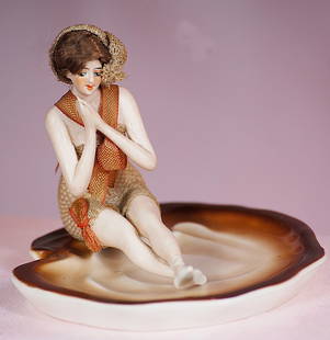 GERMAN BISQUE BATHING BEAUTY BY GALLUBA AND HOFFMAN: GERMAN BISQUE BATHING BEAUTY BY GALLUBA AND HOFFMAN. 3&#8221;. All-bisque figure of young lady in seated pose affixed to porcelain dish, posed with hands clasped in front of her and ankles crossed, pa