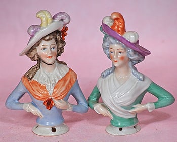 TWO GERMAN PORCELAIN HALF DOLLS WITH PLUMMED BONNETS