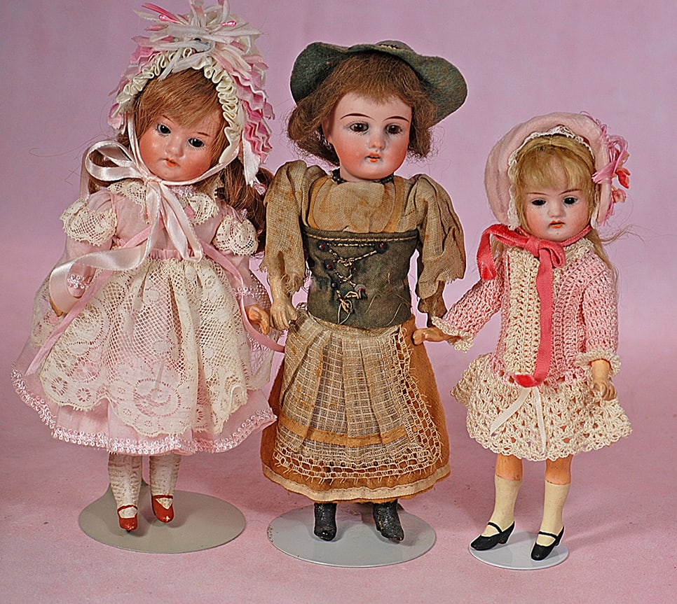 THREE SMALL GERMAN BISQUE DOLLS: THREE SMALL GERMAN BISQUE DOLLS. 7” to 8 ½”. Each is bisque socket with stationary glass eyes, open mouth, upper teeth, mohair or human hair wig, five-piece jointed paper mache/compos