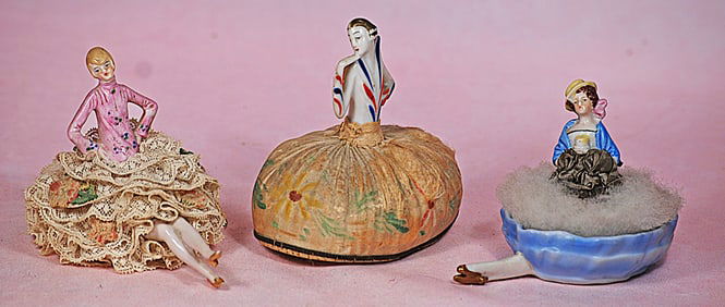 THREE GERMAN PORCELAIN HALF DOLL PINCUSHIOS AND POWDER PUFF