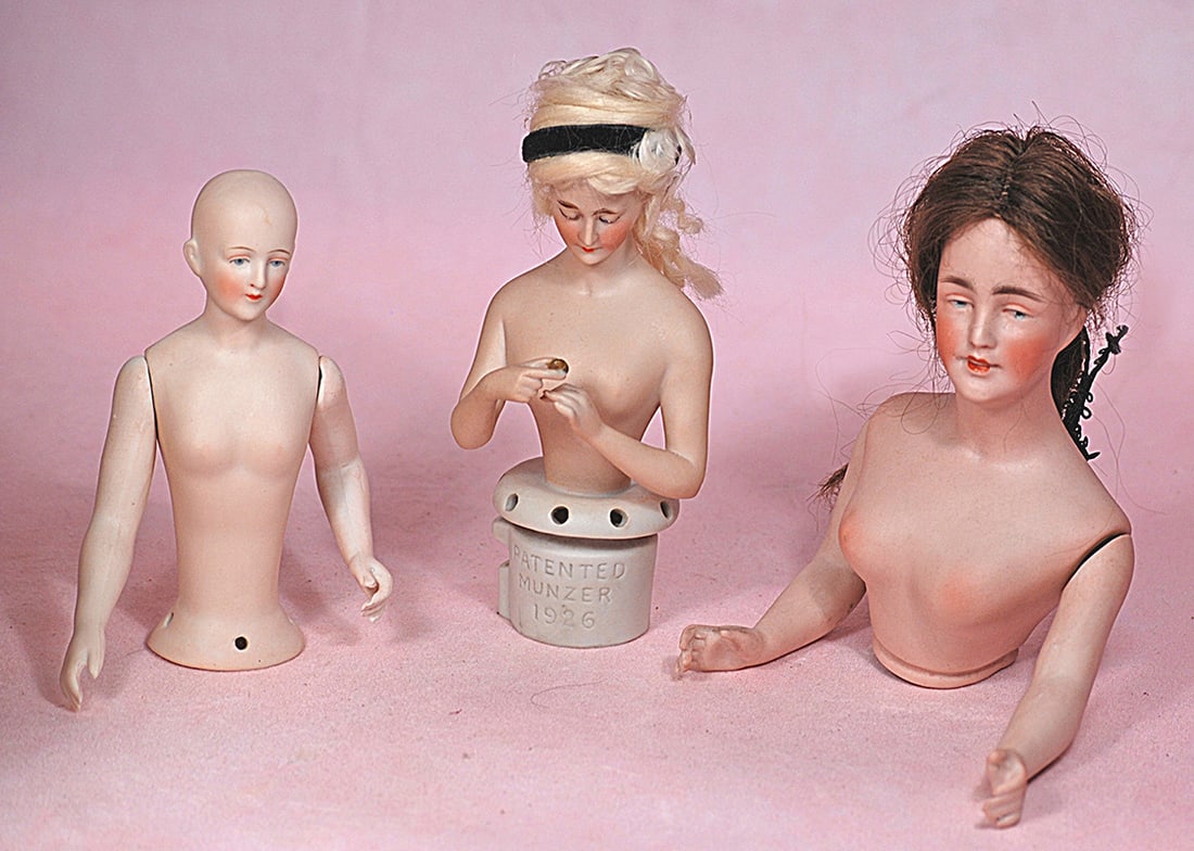 THREE GERMAN BISQUE HALF DOLLS: THREE GERMAN BISQUE HALF DOLLS. Each is waist-up bisque figure of nude lady with painted features; 5” doll with solid dome and jointed shoulders; 5 ½” doll with blonde wig, holding ri