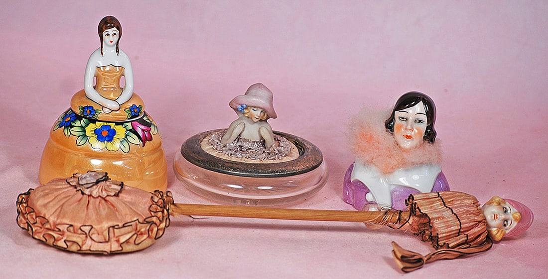 TWO POWDER PUFF HALF DOLLS, POWDER PATTER, AND DRESSER JAR: TWO POWDER PUFF HALF DOLLS, POWDER PATTER, AND DRESSER JAR. German bisque child with bonnet half doll as powder puff on round glass powder jar, 3” overall; German porcelain half doll head as pow