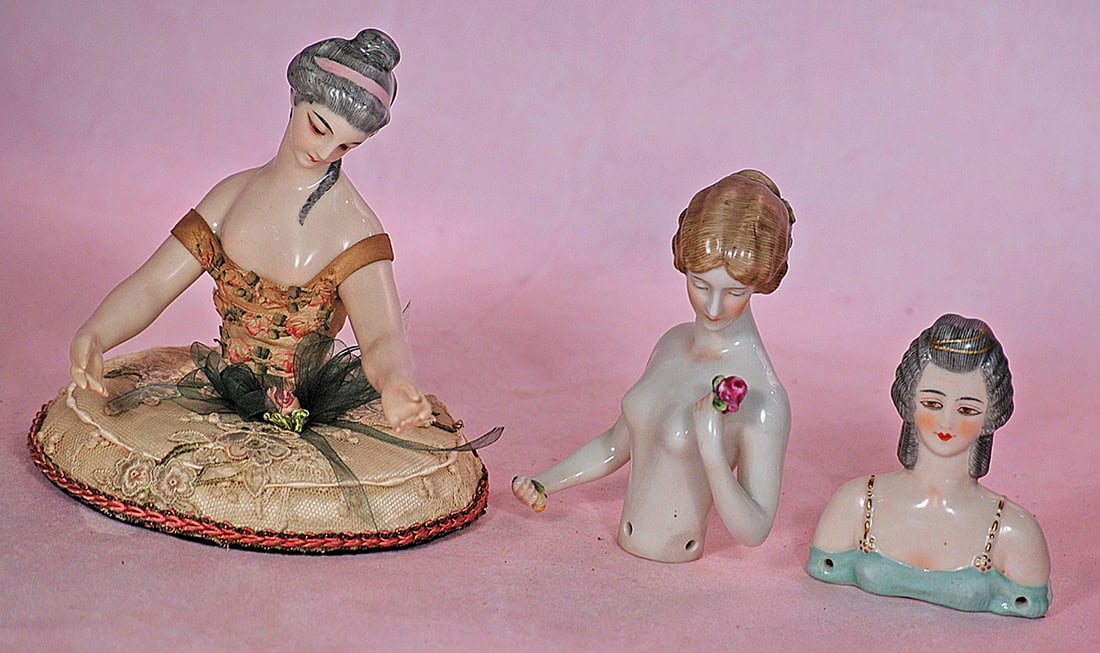 THREE GERMAN PORCELAIN HALF DOLLS: THREE GERMAN PORCELAIN HALF DOLLS. 5”waist-up nude figure of lady with sculpted gray hair and pink hair band, painted features, downward glancing eyes, arms extended away, attached to silk cover