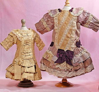 TWO DOLL DRESSES: TWO DOLL DRESSES. Beige silk French-style bebe dress, 5 ½” shoulder width, 13” length; Lavender silk French-style bebe dress, with lace trim and purple silk bow trim, 7” shoulde