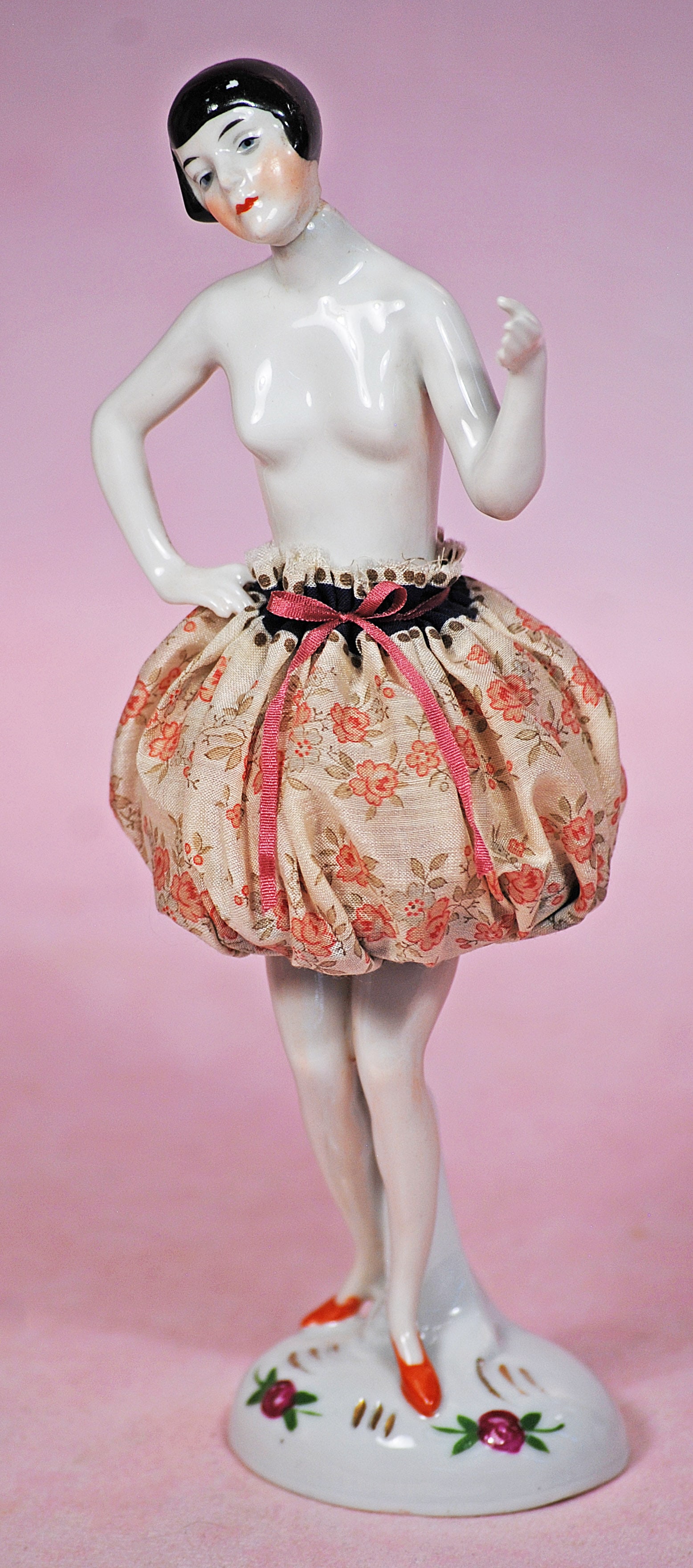 RARE SWIVEL-NECK PORCELAIN HALF DOLL PINCUSHION: RARE SWIVEL-NECK PORCELAIN HALF DOLL PINCUSHION. 8”. Porcelain swivel head, waist-up nude figure with sculpted black hair, pincushion skirt attached to porcelain legs with self base. Commentary: