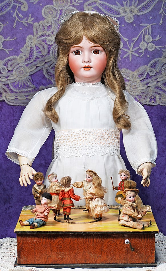 GERMAN MUSICAL MECHANICAL TOY OF DANCING DOLLS ATTRIBUTED TO ZINNER AND SOHNE.: GERMAN MUSICAL MECHANICAL TOY OF DANCING DOLLS ATTRIBUTED TO ZINNER AND SOHNE. 12” x 9”; dolls 3 ½” to 4”. Arranged on a painted wooden box are nine bisque head dolls, fou