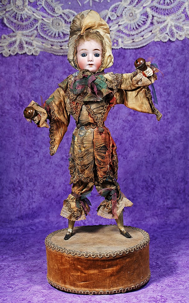 BISQUE JESTER WITH BELLS ON MUSICAL BASE.: BISQUE JESTER WITH BELLS ON MUSICAL BASE. Marks: None visible. Bisque head doll with blue glass inset eyes, painted lashes, tapered brows, open mouth, accented lips, upper teeth, original mohair wig,