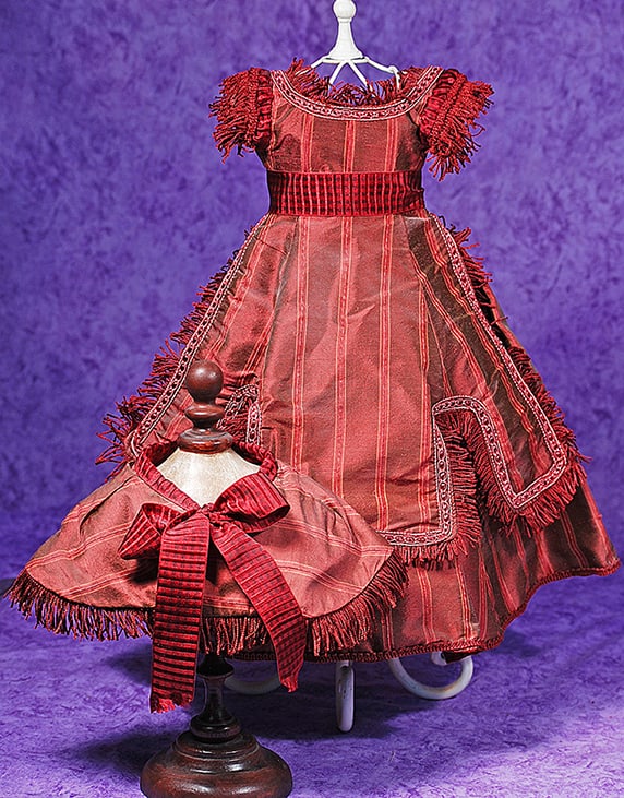ROSE SILK TAFFETA FASHION GOWN.: ROSE SILK TAFFETA FASHION GOWN. Rose and burgundy silk taffeta gown features a fitted bodice with rounded neckline, caplet sleeves with fringe trim, pleated skirt with overskirt having braid and fring