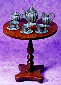 DOLLSIZE WOODEN TILT TOP TABLE WITH MINIATURE PEWTER TEA SERVICE.