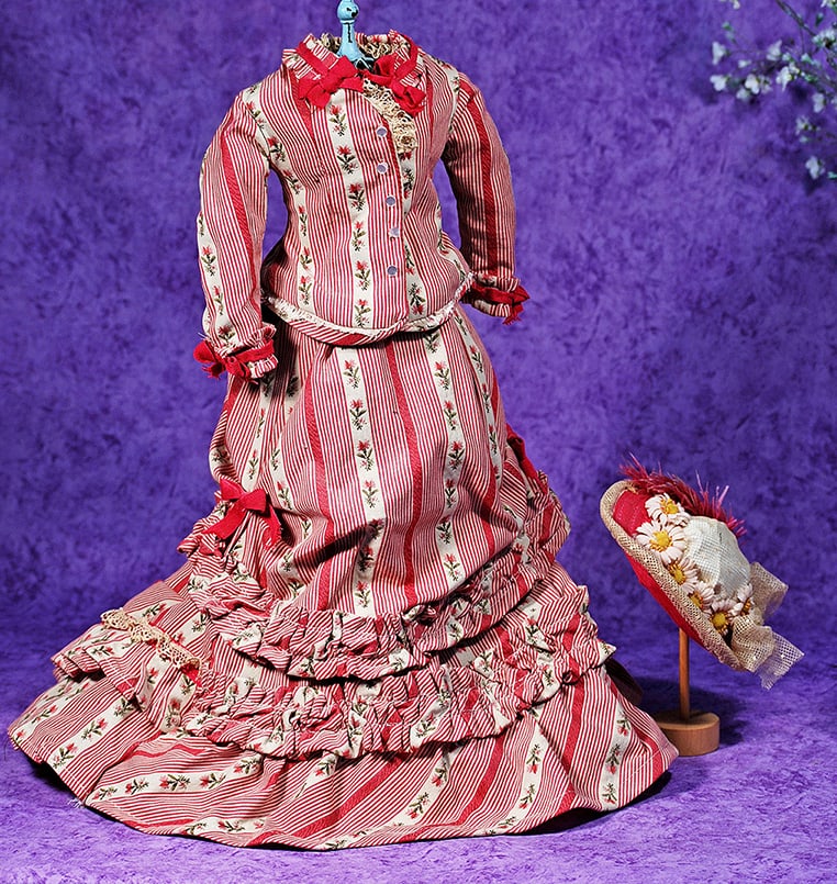 FASHION GOWN AND BONNET.: FASHION GOWN AND BONNET. Two piece gown comprised of fitted jacket with long sleeves, button front closing, pleated trim and silk ribbon trim, pleated skirt with bustled back and rows of ruffles accen