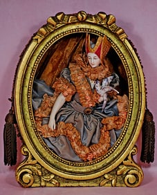 FRAMED GERMAN PORCELAIN HALF DOLL WITH JOINTED ARMS, RARE HEADDRESS AND HOLDING A BIRD.