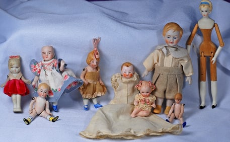 MINIATUE PEG WOODEN DOLL BY SHERMAN SMITH AND EIGHT TINY ALL-BISQUE DOLLS