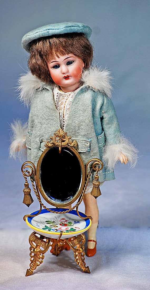 MINIATURE GILDED METAL VANITY: 5 ¼”. Ornate gilded metal footed vanity with painted china plate, oval beveled mirror and gilded supports.