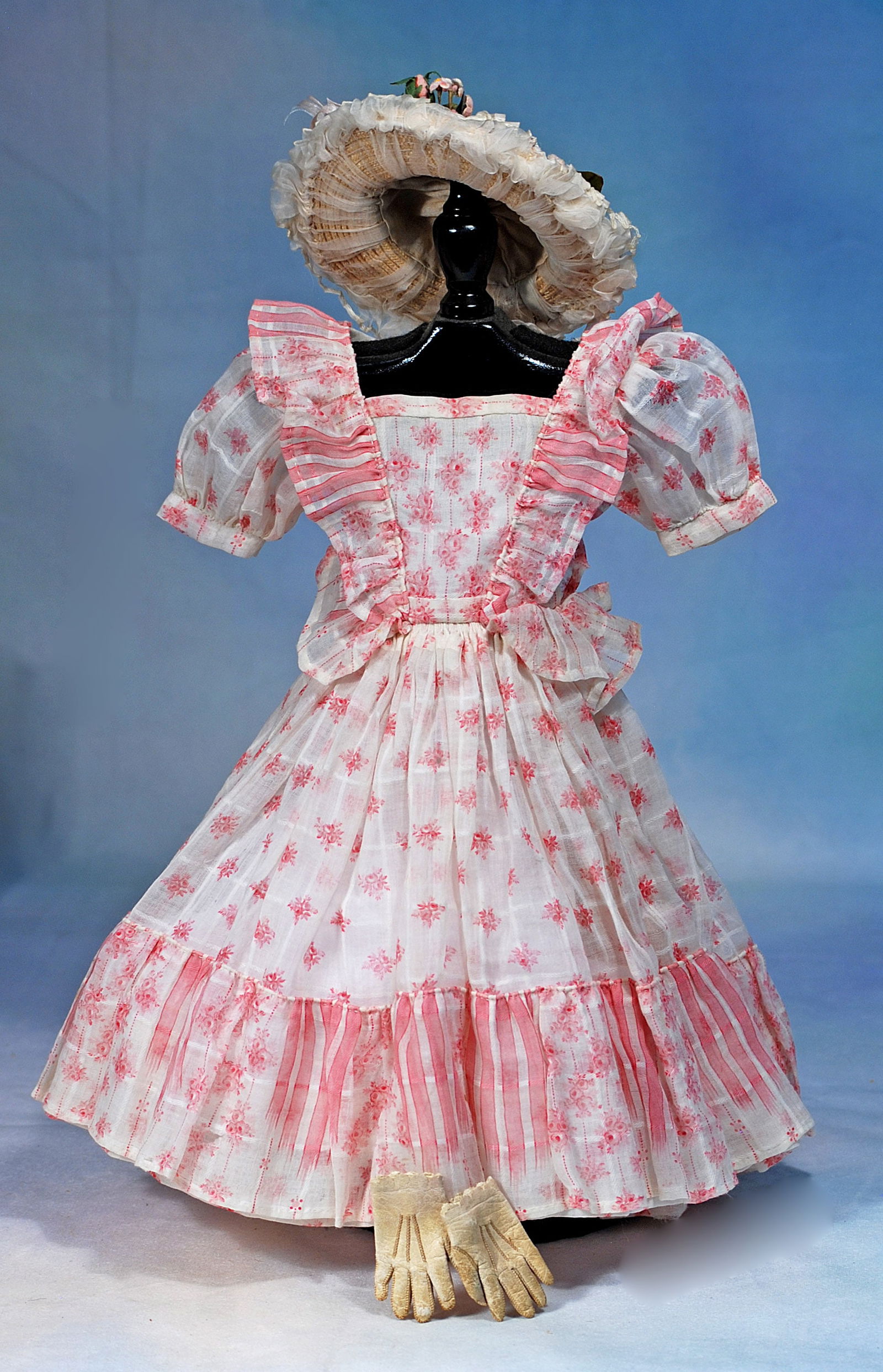 FINE PINK AND WHITE DRESS FOR POUPEES: Fashioned of fine cotton print and decorated with flounces and furbelows in the French manner, back hook-eye closing, sized for 17” poupee; matching straw bonnet with pastel flowers, and pair