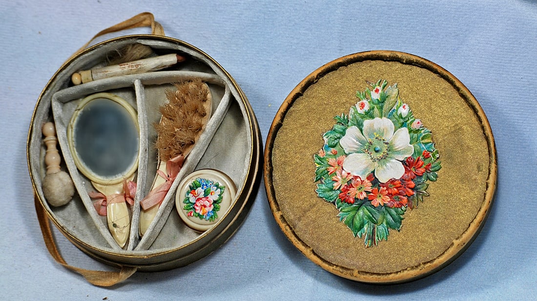 MINIATURE DOLL’S TOILETTE SET IN ORIGINAL BOX: 3 ½” round cardboard box with divided interior containing comb, brush, powder box and more.