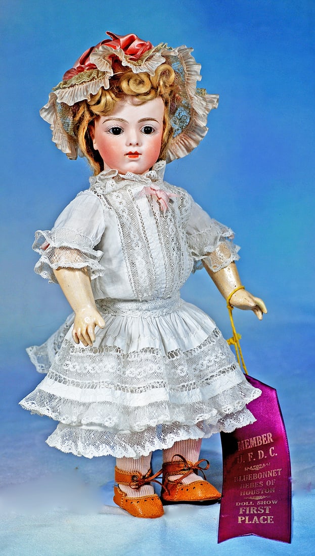 PETITE FRENCH BISQUE, SIZE 4, BRU JNE BEBE: 12”. Marks: Bru Jne 4. Bisque socket head, dark brown paperweight eyes, painted lashes, feathered brows, pierced ears, closed mouth, blonde mohair wig, composition and wooden jointed