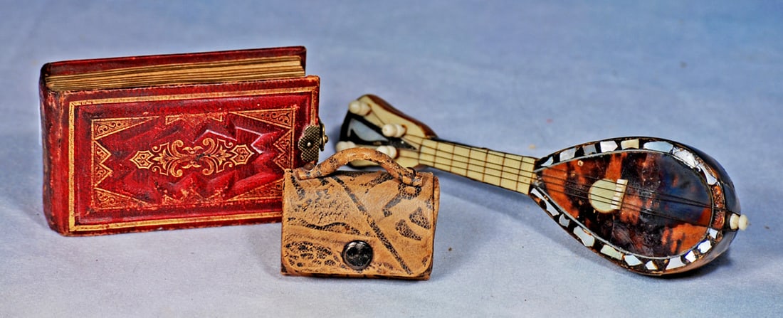 MINIATURE TORTOISE SHELL INSTRUMENT, TINTYPE ALBUM AND PURSE: Beautiful 6” tortoise shell mandolin with bone and mother-of-pearl inlays plus strings and tiny turning handles; 3 ¼” x 1 ¾” red leather-bound album with embossed gilt
