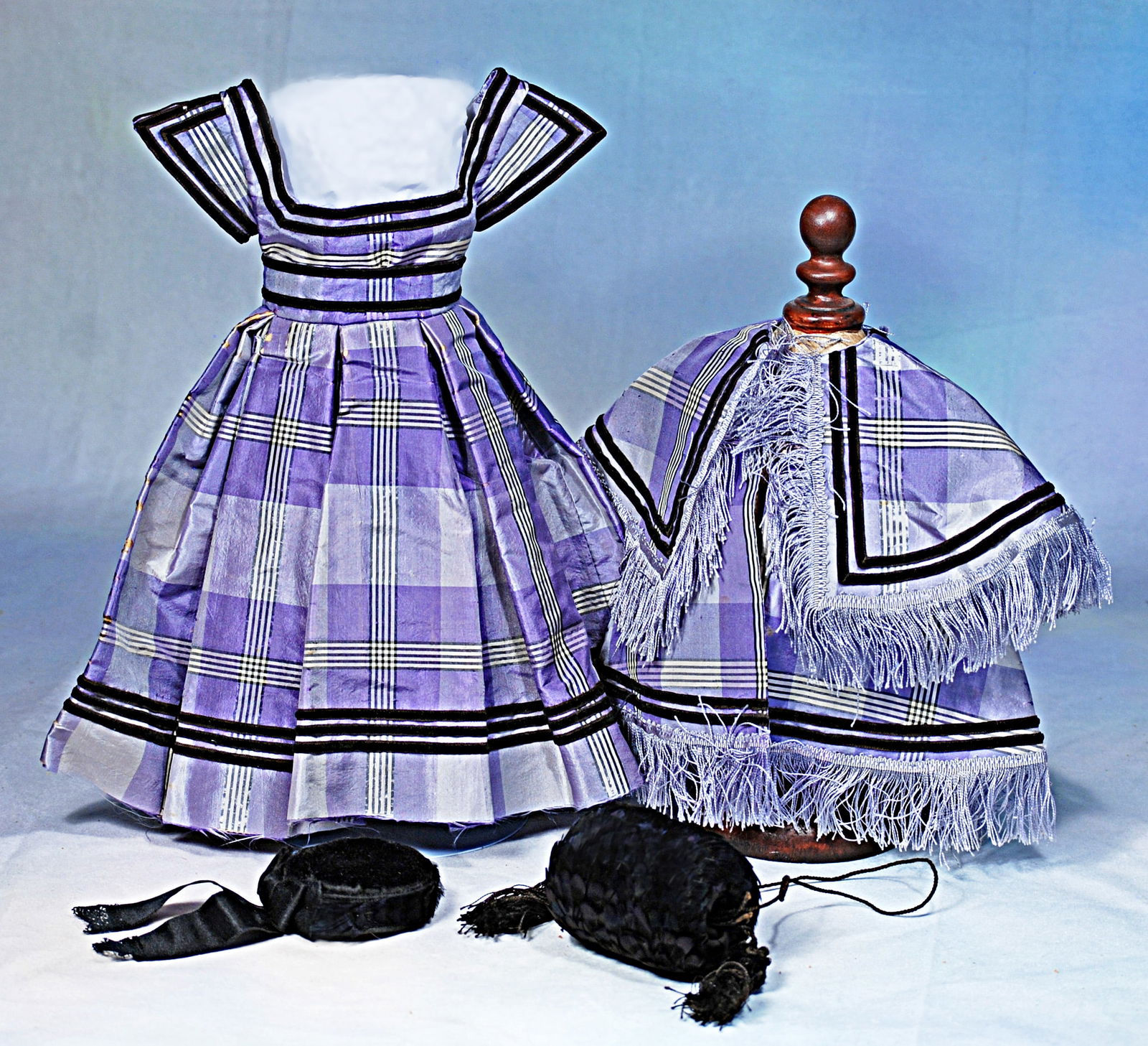 LAVENDER SILK TAFFETA GOWN AND ACCESSORIES IN THE HURET MANNER: Sized for 17” poupee. Lavender silk taffeta with bands of white and black detail further accented with narrow black velvet trim, bow with scalloped edging at back, fitted bodice and